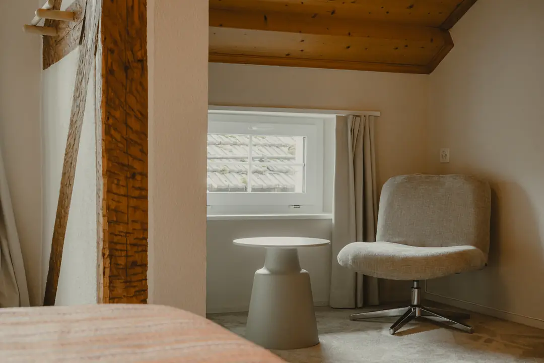 Chambre Deluxe vue Montagne : un fauteuil et une petite table sous le toit