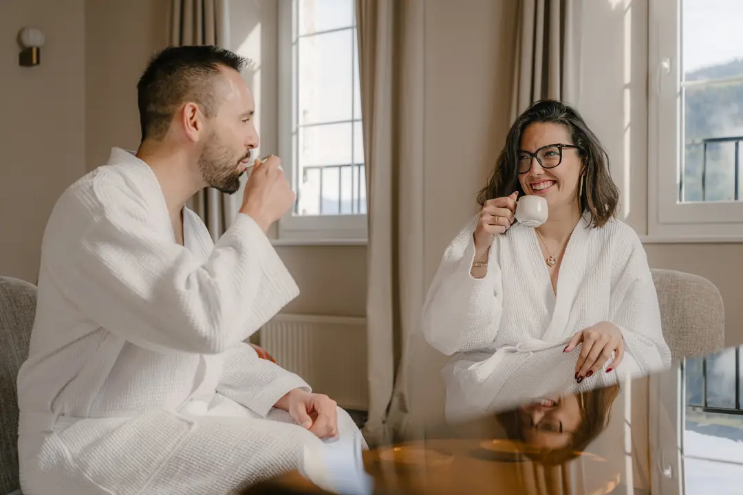 Deux hôtes en peignoir prennent le café près de la fenêtre
